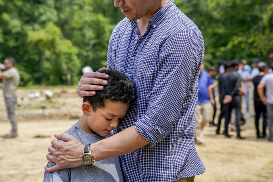 Asem Ahmad Yar, 8, son of Nasrat Ahmad Yar, 31, is comforted by a family friend during the funeral service for his father at the All Muslim Association of America cemetery on Saturday, July 8, 2023 in Fredericksburg, Va. Ahmad Yar, an Afghan immigrant who worked as an interpreter for the U.S. military in Afghanistan, was shot and killed on Monday, July 3, while working as a ride-share driver in Washington. (AP Photo/Nathan Howard)