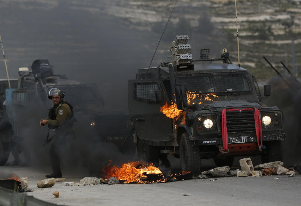Israeli border policemen move away from a burning vehicle during clashes with Palestinians at checkpoint Bet El near the West Bank city of Ramallah , Wednesday, March 27, 2019.(AP Photo/Majdi Mohammed)