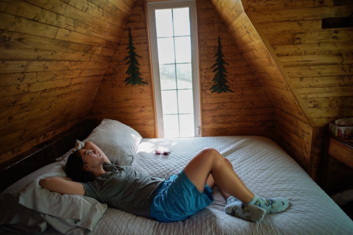 The author lays on the bed in the treehouse