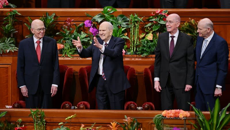 President Russell M. Nelson of The Church of Jesus Christ of Latter-day Saints holds his hands out and gestures toward the audience as he and his counselors, President Dallin H. Oaks, first counselor in the First Presidency, left, and President Henry B. Eyring, second counselor in the First Presidency, take their seats prior to the afternoon session of the 194th Annual General Conference of The Church of Jesus Christ of Latter-day Saints at the Conference Center in Salt Lake City on Sunday, April 7, 2024.