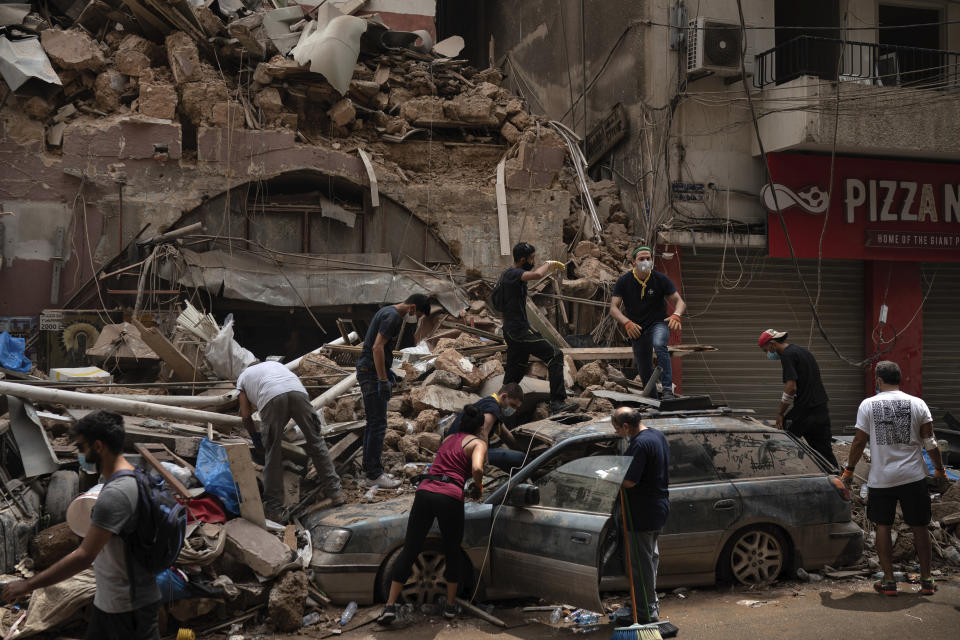 People remove debris from a house damaged by Tuesday's explosion in the seaport of Beirut, Lebanon, Friday, Aug. 7, 2020. Rescue teams were still searching the rubble of Beirut's port for bodies on Friday, nearly three days after the massive explosion sent a wave of destruction through Lebanon's capital. (AP Photo/Felipe Dana)