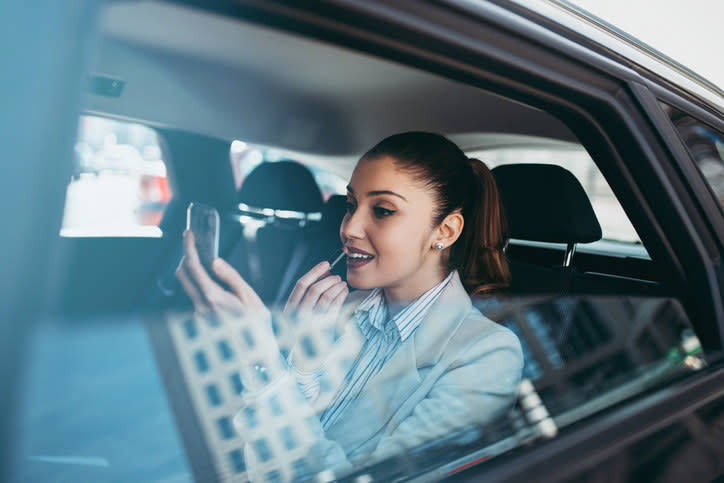 A woman doing her makeup in the car