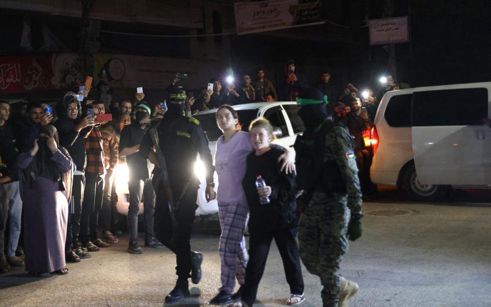 Hamas fighters accompany newly released hostages before handing them over to the Red Cross in Rafah, in the southern Gaza Strip on November 28, 2023.
