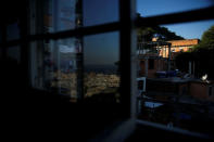 Houses (R) are seen through a window as Copacabana beach is reflected on a glass at Tiki hostel in Cantagalo favela, in Rio de Janeiro, Brazil, April 15, 2016. REUTERS/Pilar Olivares