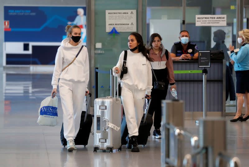 Tourists walk with their luggage as they arrive at Malaga-Costa del Sol Airport, in Malaga