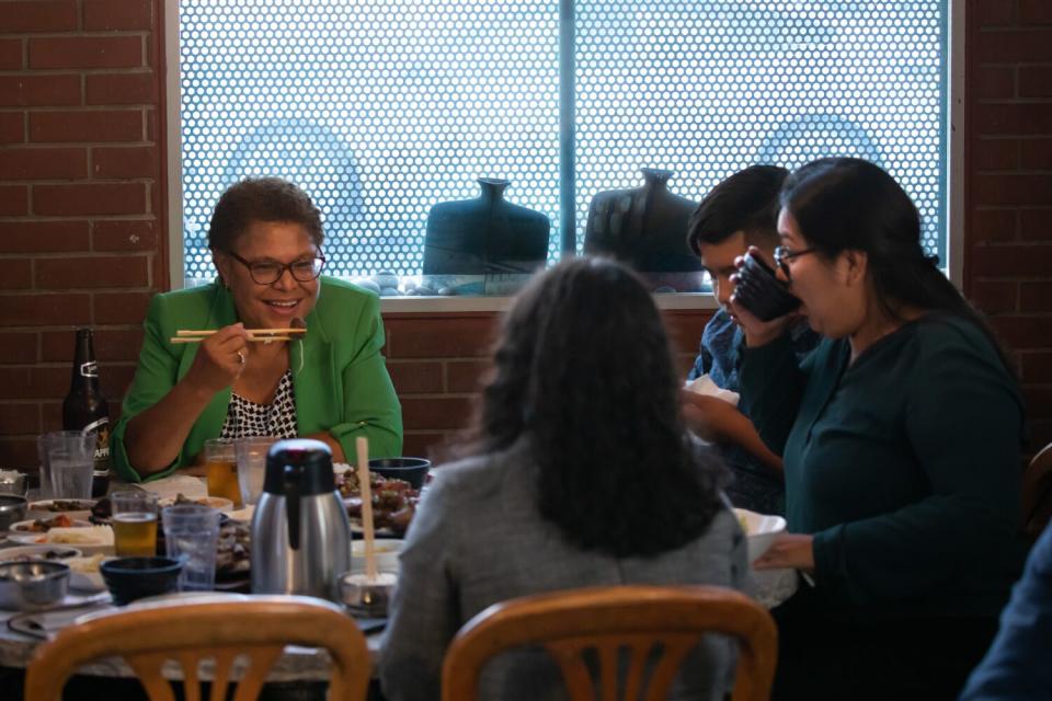 Four sit around a big table full of food in a restaurant.