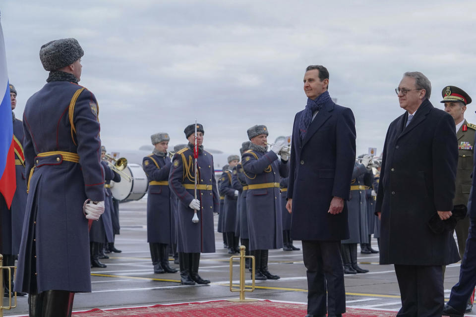 In this photo released by the Syrian official news agency SANA, visiting Syrian President Bashar Assad, left, and Mikhail Bogdanov, right, Deputy Minister of Foreign Affairs of Russia and Special Representative of the President of Russia for the Middle East, review an honor guard during a welcome ceremony upon Assad's arrival at Vnukovo airport in Moscow, Russia, Tuesday, March 14, 2023. Assad on Tuesday landed in Russia where he is scheduled to meet top ally President Vladimir Putin. (SANA via AP)