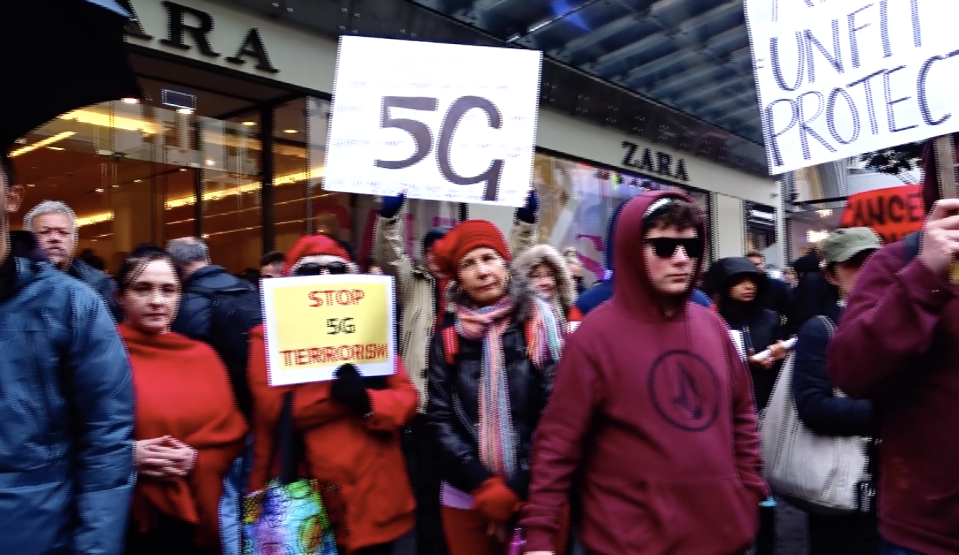 5G protestors in Melbourne are pictured holding signs that read 'Stop 5G terrorism' and demanding protection. 