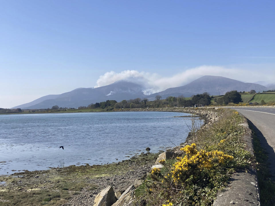 A view ofthe gorse fire spreading across the Mourne Mountains in the background, seen from Newcastle, County Down, in Northern Ireland, Saturday, April 24, 2021. Firefighters in Northern Ireland are spending a second day batting fires through demanding terrain on the Mourne Mountains. Helicopters from both Britain and Ireland are set to join the effort Saturday to put out the fires. They have been raging since Friday morning in the Slieve Donard area — the highest point in Northern Ireland with a peak of 850 meters (2,780 feet). (Rebecca Black/PA via AP)