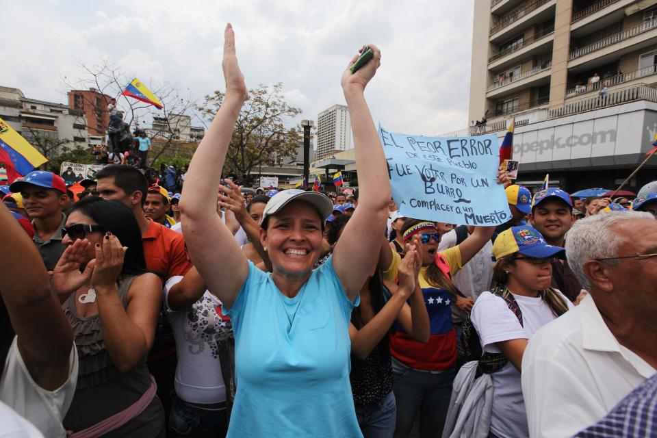 A supporter of Maria Corina Machado cheers during a rally in Caracas, Venezuela, Tuesday, April 1, 2014. Protesters wearing white T-shirts and hats in the red, yellow and blue, of Venezuela's flag have gathered to cheer the opposition leader who was stripped of her seat in congress by the government last week. This is Machado's first major public appearance since Venezuela's Supreme Court confirmed the stripping of Machado's parliamentary seat after she addressed the Organization of American States at the invitation of Panama. (AP Photo/Fernando Llano)