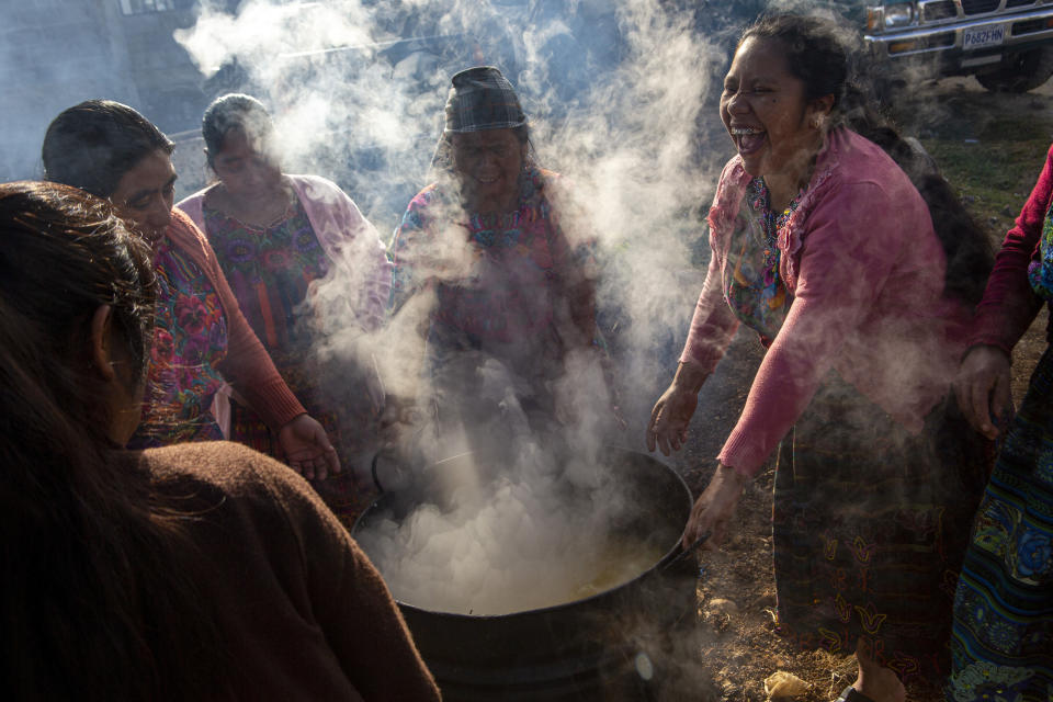 Mujeres revuelven una olla de maíz hervido para hacer tortillas para el velatorio de Aurelio Cuy Tamat en Santa Apolonia, Guatemala, el viernes 31 de diciembre de 2021. (AP Foto/Oliver de Ros)