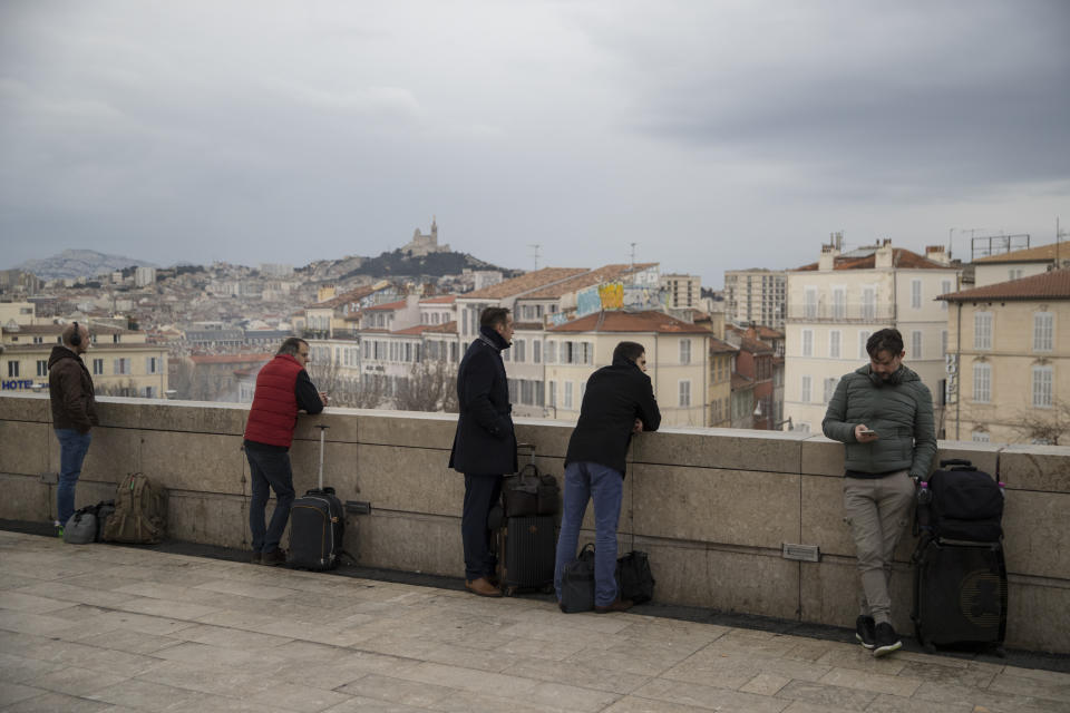 Travelers observe strikers marching during a demonstration from the entrance of the Gare St-Charles station in Marseille, southern France, Friday, Jan. 24, 2020. French unions are holding last-ditch strikes and protests around the country Friday as the government unveils a divisive bill redesigning the national retirement system. (AP Photo/Daniel Cole)