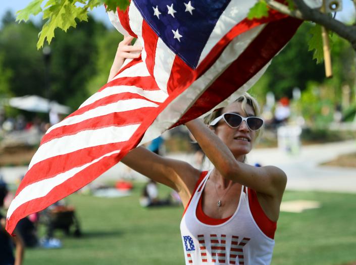 Guests took the opportunity to celebrate the Fourth of July at Greenville's Unity Park.  Rachel Williams, 30, who just moved to Travelers Rest, hangs a flag in a tree near the spot her family will gather.