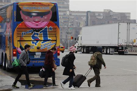 Passengers cross a street to catch a Megabus bus parked on the other side of the street in New York City May 8, 2014. REUTERS/Eduardo Munoz