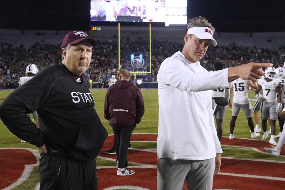 Mississippi State coach Mike Leach, left, watches as Mississippi coach Lane Kiffin directs photographers away from their pregame meeting at an NCAA college football game in Oxford, Miss., Thursday, Nov. 24, 2022. (AP Photo/Rogelio V. Solis)