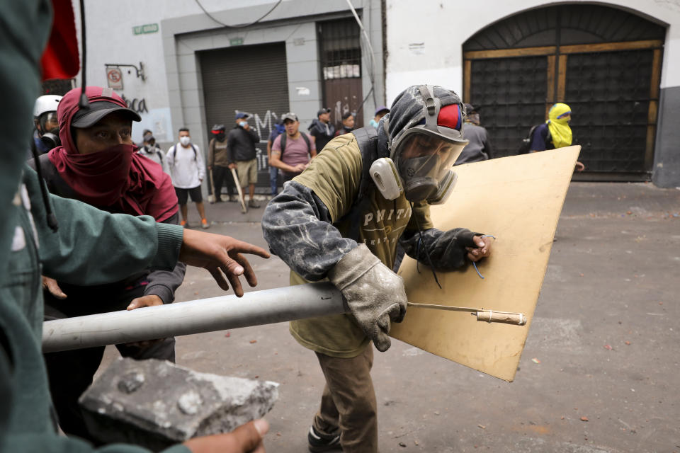 Protesters prepare a makeshift firework launcher during clashes with security forces in downtown Quito, Ecuador, Wednesday, Oct. 9, 2019. Violence started last week after President Lenin Moreno ended fuel subsidies, leading to price increases. Disturbances have spread from transport workers to students and then to indigenous demonstrators. (AP Photo/Fernando Vergara)
