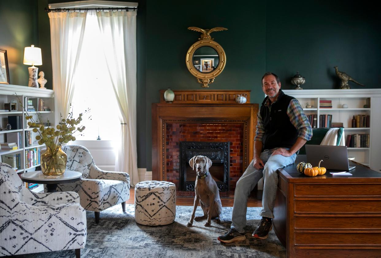 Drew Musser, owner, of The Willis-James Bed and Breakfast sits on the desk in one the downstairs rooms with his Weimaraner, Dante, on October 18, 2023, in Chillicothe, Ohio.