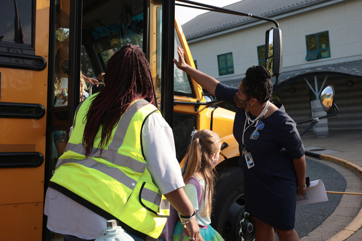 ARLINGTON, VIRGINIA - AUGUST 30: Ms. Carolyn Jackson, Assistant Principal of Long Branch Elementary School, greets students as the walk off the school bus on August 30, 2021 in Arlington, Virginia. Today is the first day of the school year for Arlington Public Schools after students participated in a hybrid learning schedule in the spring semester of 2021 due to the the Covid-19 pandemic.  (Photo by Anna Moneymaker/Getty Images)