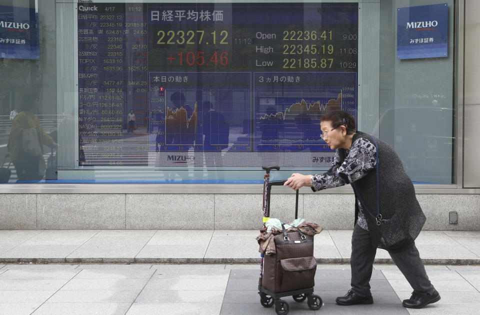 Elderly woman walks by an electronic stock board of a securities firm in Tokyo, Wednesday, April 17, 2019. Shares were mixed in a narrow range Wednesday as China announced its economy grew at a 6.4 percent annual pace in the last quarter. (AP Photo/Koji Sasahara)