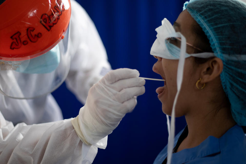 A nurse gets a swab from a health worker in a booth set up in a hospital parking lot as the Philippines ramps up testing for coronavirus disease (COVID-19) in Manila, Philippines, April 15, 2020. REUTERS/Eloisa Lopez