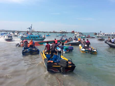 Rescue team personnel stand on a boat as they try to save the victims of capsized boat in Tarakan, North Kalimantan, Indonesia July 25, 2017 in this photo taken by Antara Foto. Antara Foto/Iskandar Z Daru via REUTERS