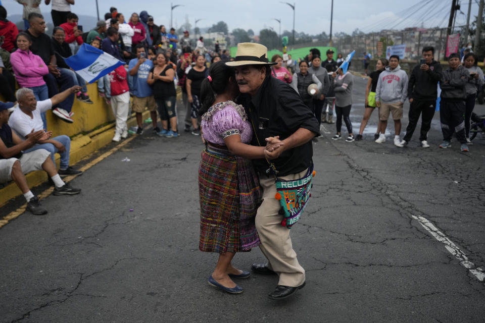 Una pareja baila en mitad de una carretera en una manifestación en Ciudad de Guatemala el lunes 9 de octubre de 2023. Las protestas en respaldo del presidente electo Bernardo Arévalo reclaman por las acciones de la fiscalía y judiciales contra su partido para suspenderlo por presuntamente haberse constituido con firmas falsas. (AP Foto/Moisés Castillo)