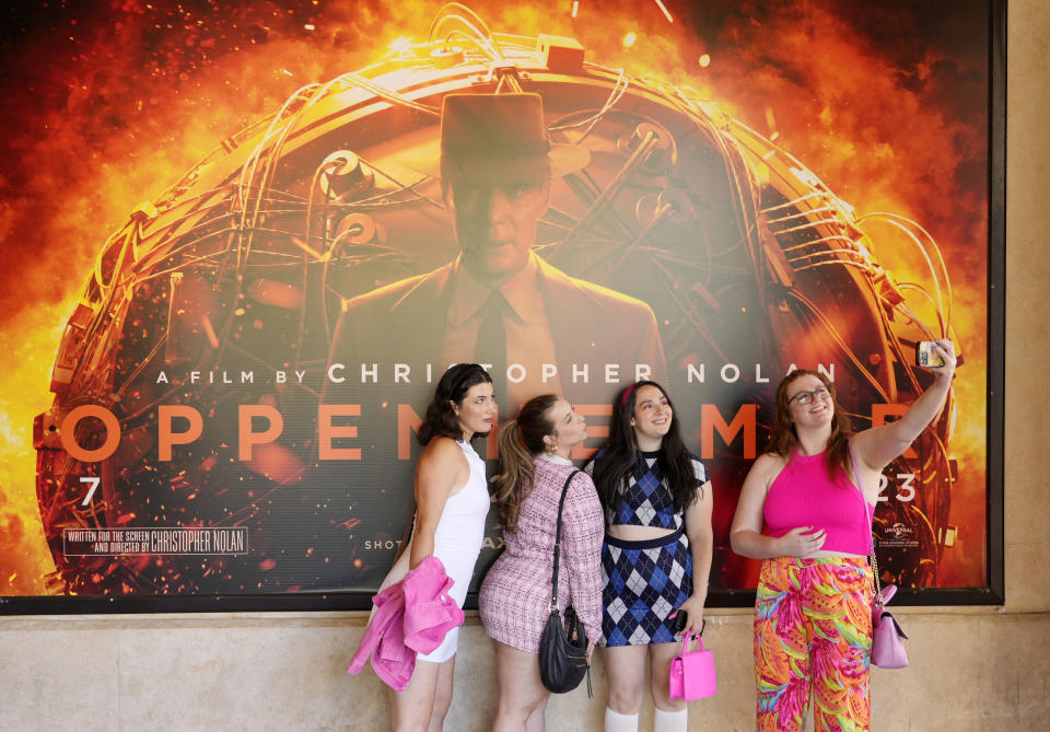 Gabrielle Roitman, de izquierda a derecha, Kayla Seffing, Maddy Hiller y Casey Myer se toman una selfie frente a un cartel de la película "Oppenheimer" antes de asistir a una proyección anticipada de "Barbie", el jueves 20 de julio de 2023 en los cines AMC The Grove 14 en Los Ángeles. (Foto AP/Chris Pizzello)