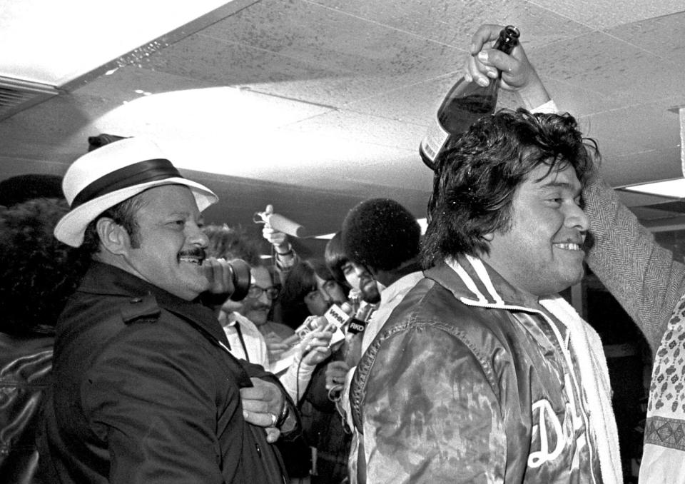 Dodgers scout Mike Brito looks on as pitcher Fernando Valenzuela celebrates in the clubhouse.