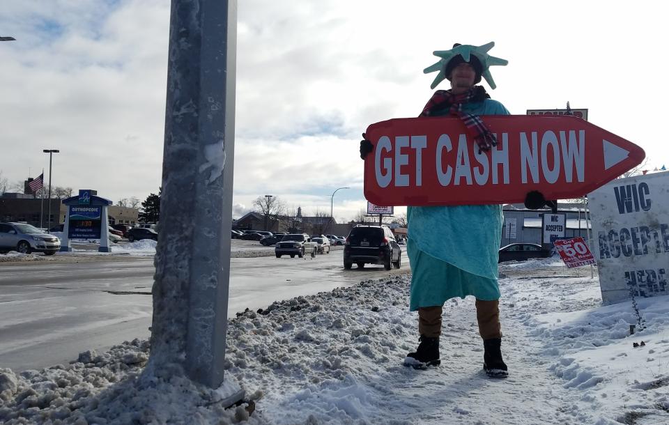 Dressed as Lady Liberty, Brandon Williams holds a sign to Liberty Tax Service outside the Tenth Street office in Port Huron on Monday, Jan. 21, 2019. Williams said he didn't mind working in the day's chilly weather.