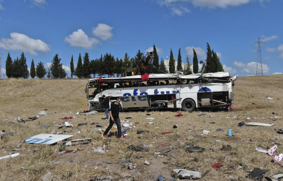 Officials investigate at the site of a bus crash, in Balikesir, western Turkey, Sunday, Aug. 8, 2021. A passenger bus has veered and tumbled off a highway in western Turkey, killing 14 people. The governor’s office of Balikesir province said said the bus overturned at 04:40 local time (0140 GMT) on Sunday. ( IHA via AP)