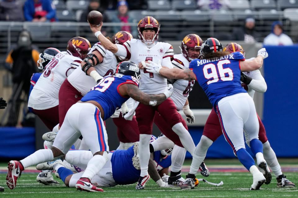 Washington Commanders quarterback Taylor Heinicke (4), center, throws under pressure from New York Giants' defenders during the second half of an NFL football game, Sunday, Dec. 4, 2022, in East Rutherford, N.J. (AP Photo/John Minchillo)