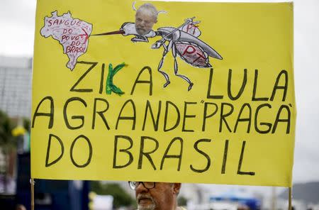 A demonstrator carries a poster during a protest against Brazil's President Dilma Rousseff, part of nationwide protests calling for her impeachment, at Copacabana beach in Rio de Janeiro, Brazil, March 13, 2016. The poster reads, "Zika and Lula are the plague of Brazil", in reference to Brazil's former president Luiz Inacio Lula da Silva. REUTERS/Ricardo Moraes