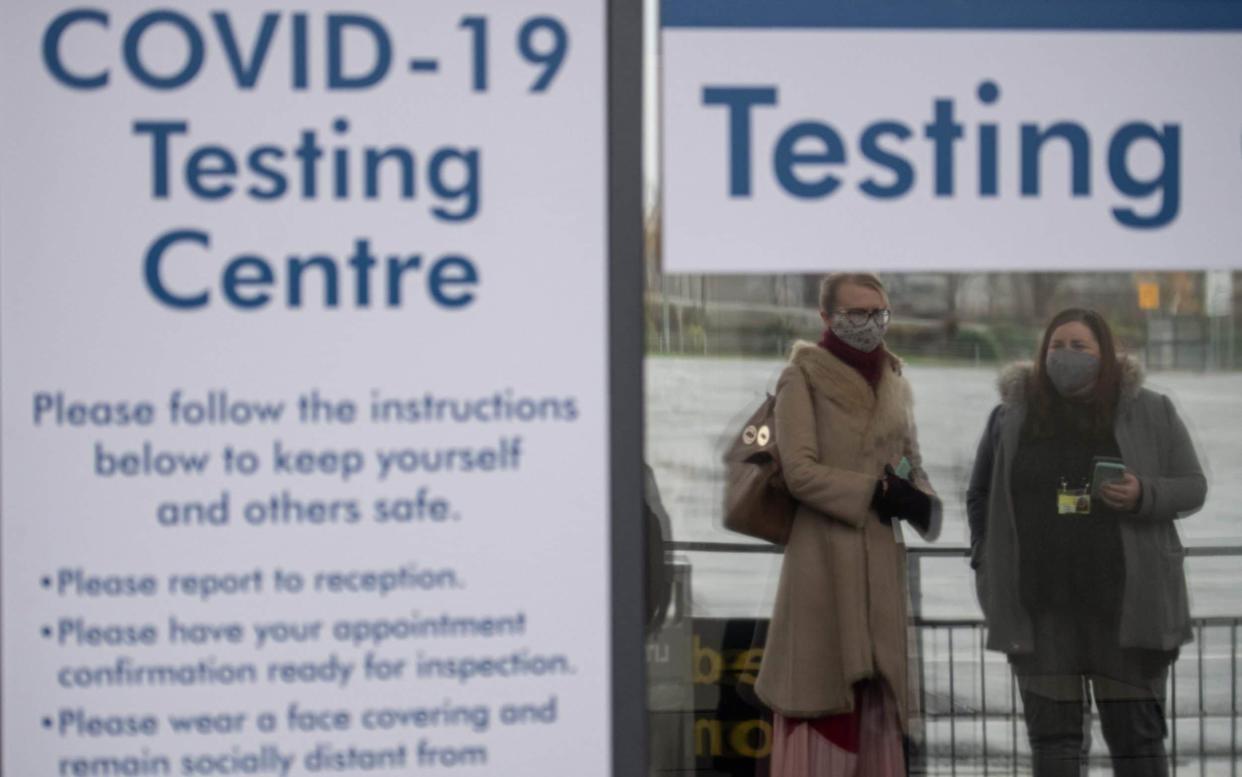 People wait outside a coronavirus testing centre in Manchester - Oli Scarff/AFP