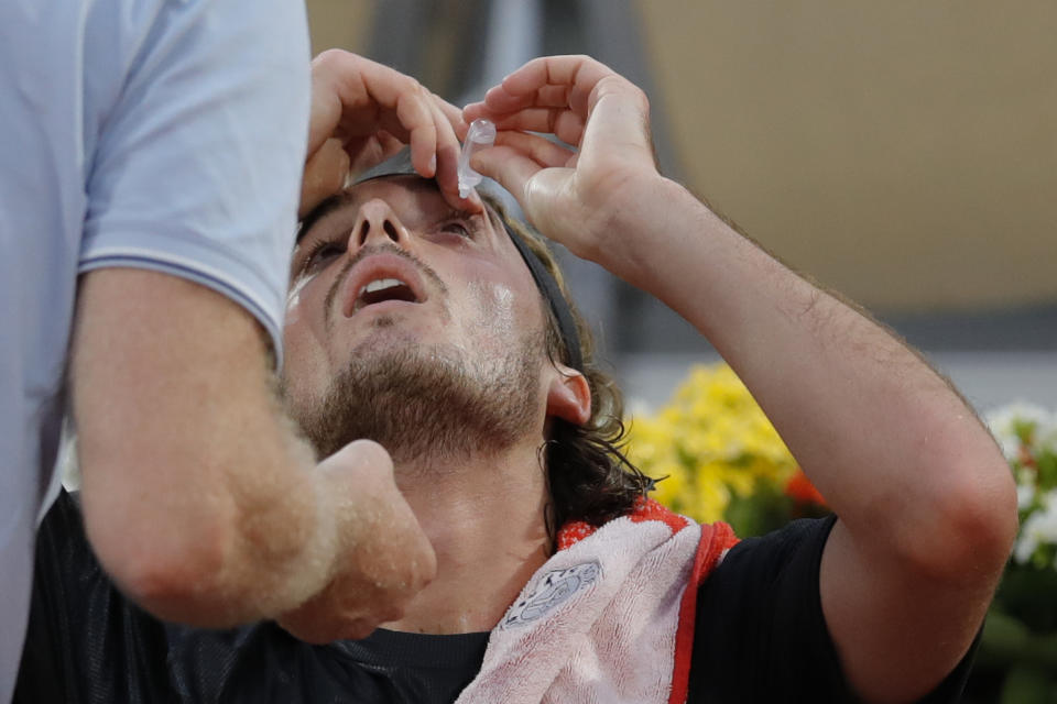 Greece's Stefanos Tsitsipas gets medical assistance for dust in his left eye in the first round match of the French Open tennis tournament against Spain's Jaume Munar at the Roland Garros stadium in Paris, France, Tuesday, Sept. 29, 2020. (AP Photo/Christophe Ena)