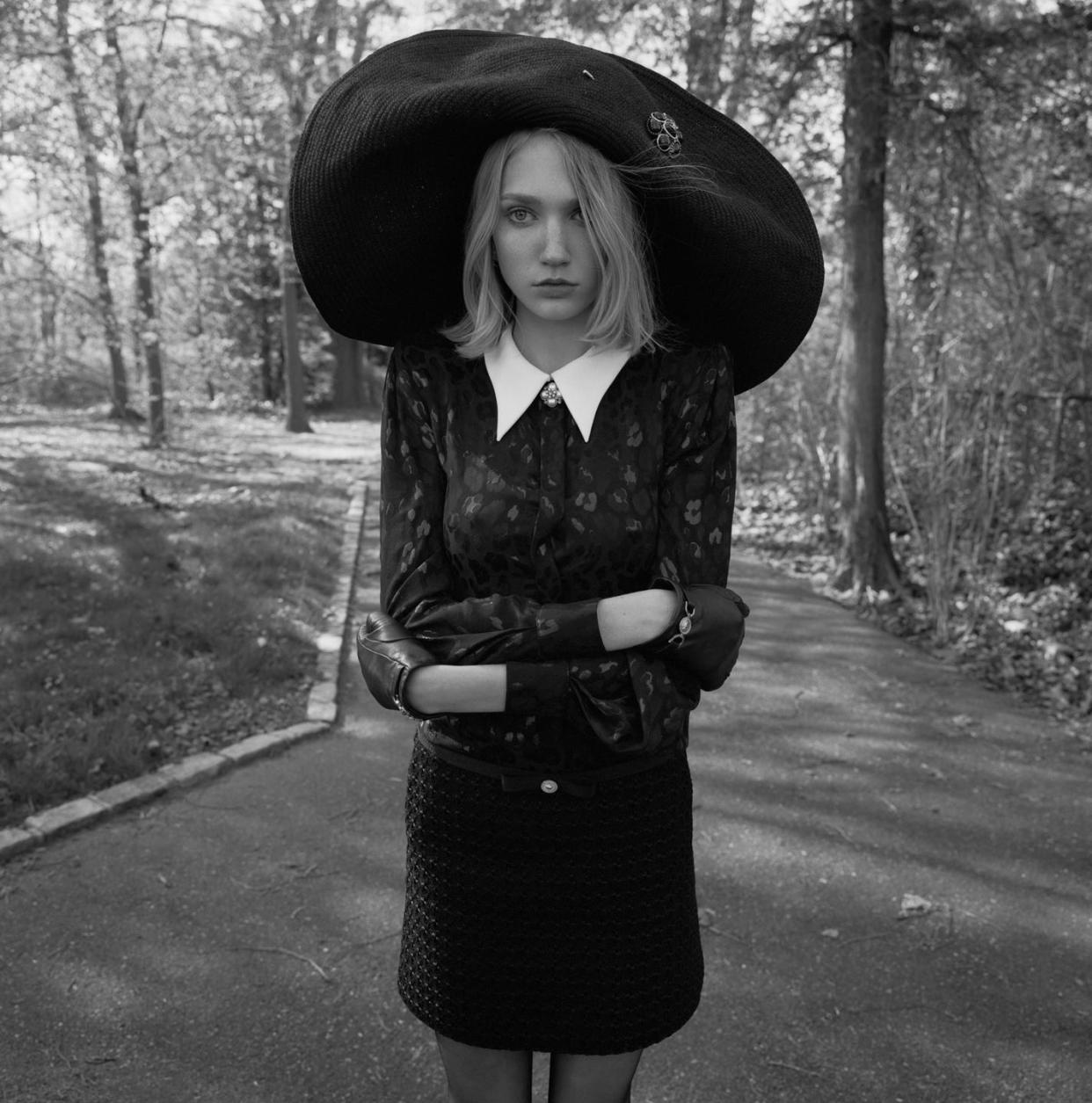 a woman in a black dress and oversized hat