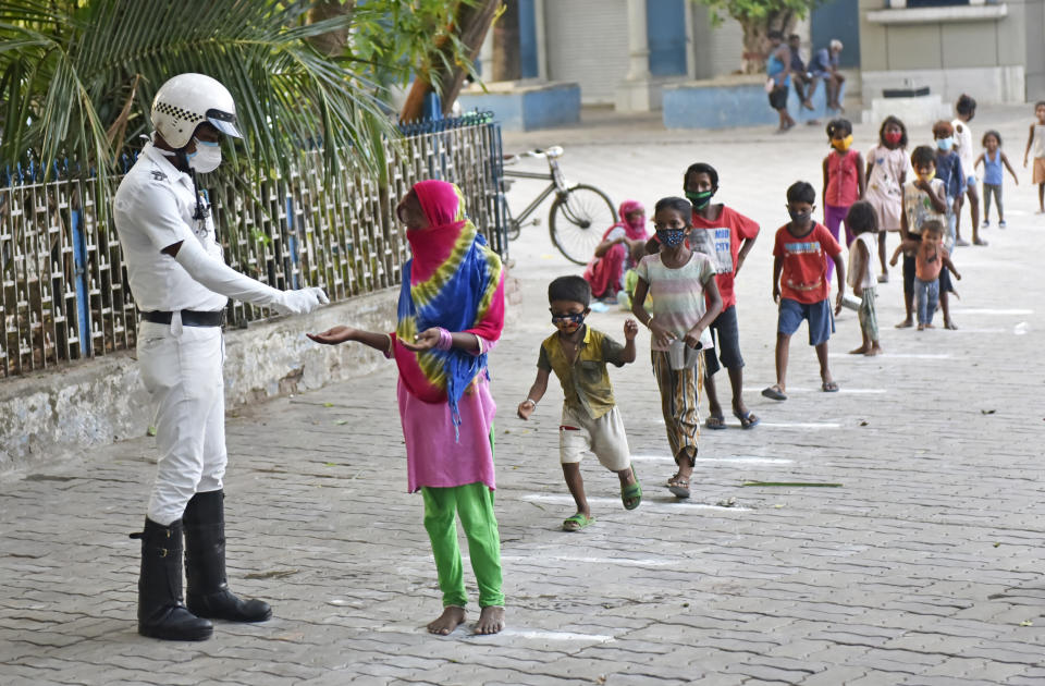 A policeman sanitizes a hand of a poor child who stands in a line during a free glass of milk and biscuit packet distribution organised by Kolkata police amid coronavirus emergency in Kolkata, India, 23 May, 2021. India has surpassed Nigeria when it comes to having the largest population of people living in extreme poverty. India added another 85 million poor to its existing huge numbers that have somehow been surviving below the poverty line. The devastating second wave of Covid-19 may leave a still bigger dent in poverty estimates according to an Indian media report.      (Photo by Indranil Aditya/NurPhoto via Getty Images)