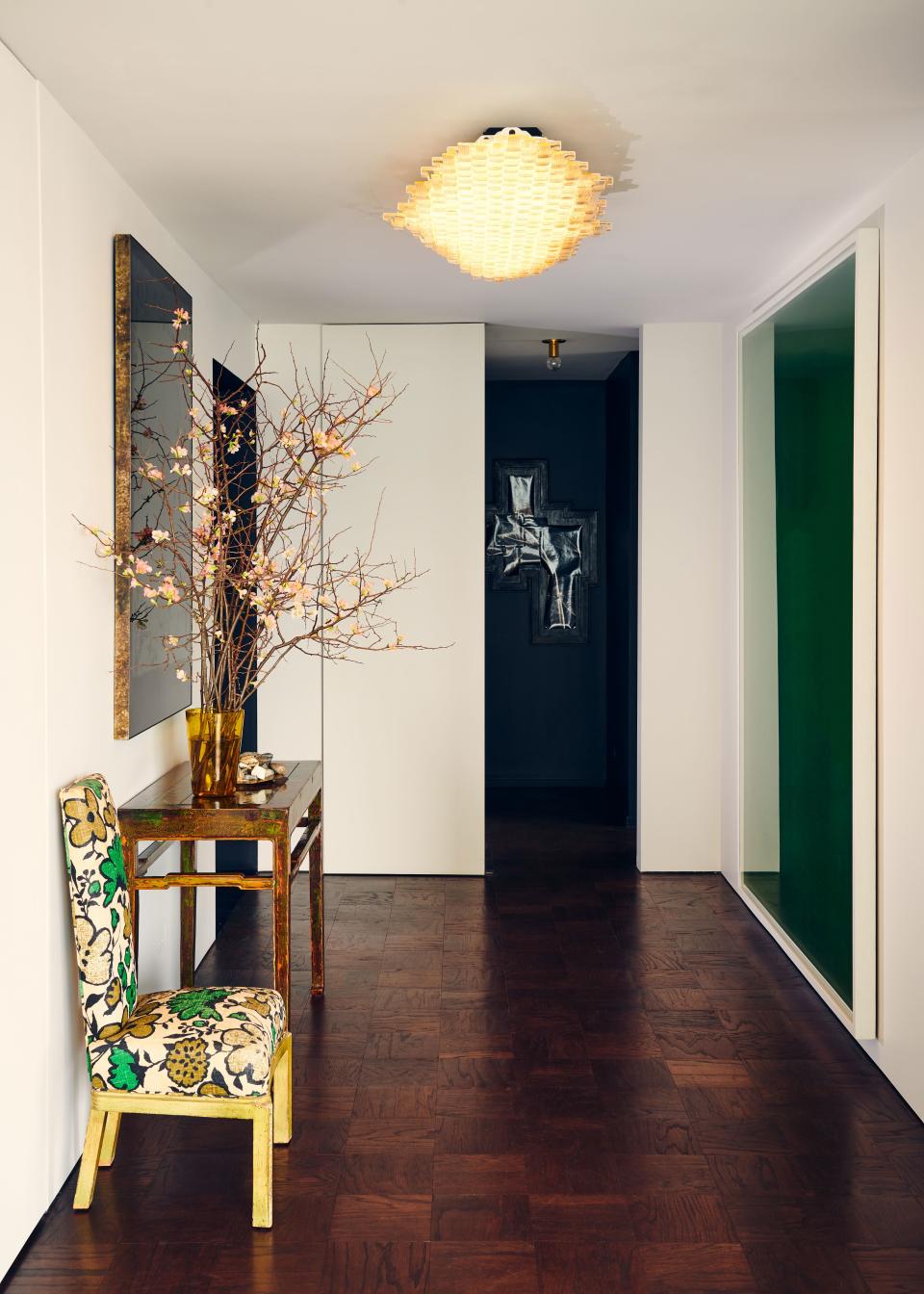 Another distinctive light fixture is seen in the foyer. Called Lace No. 1, this mounted piece was made by Coma Studio using salvaged pieces of glass from the 1950s found at the now-defunct Hotel Bristol in Italy. The green tones in the vintage James Mont chair are echoed in the large Wolfgang Tillmans print on the opposite wall.