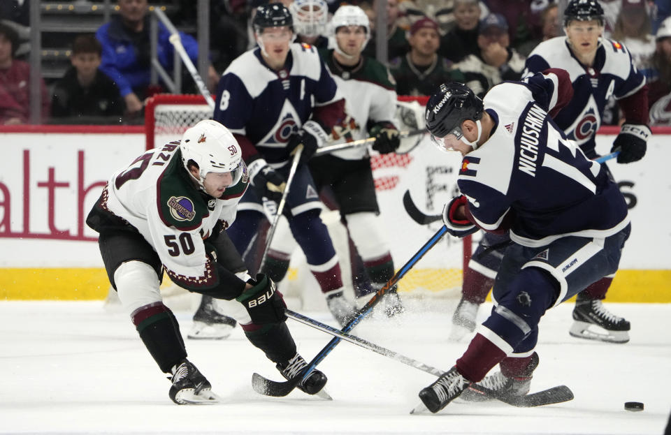 Arizona Coyotes defenseman Sean Durzi (50) knocks the puck away from Colorado Avalanche right wing Valeri Nichushkin (13) in the first period of an NHL hockey game Saturday, Dec. 23, 2023, in Denver. (AP Photo/David Zalubowski)