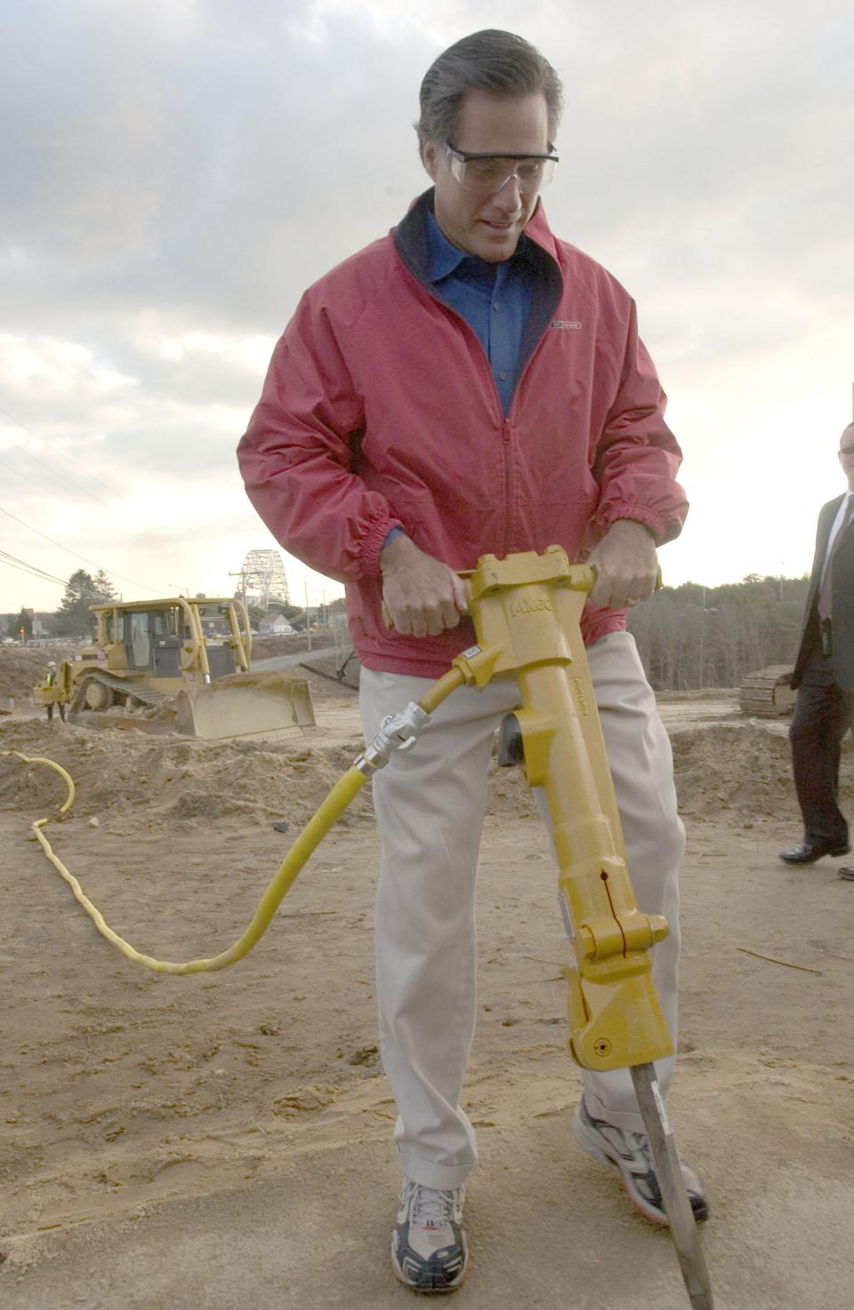 In this Dec. 3, 2004 photo, then-Gov. Mitt Romney works a jackhammer to break up a ceremonial piece of asphalt to mark the start of the Sagamore flyover project that replaced the rotary on the mainland side of the Sagamore Bridge.