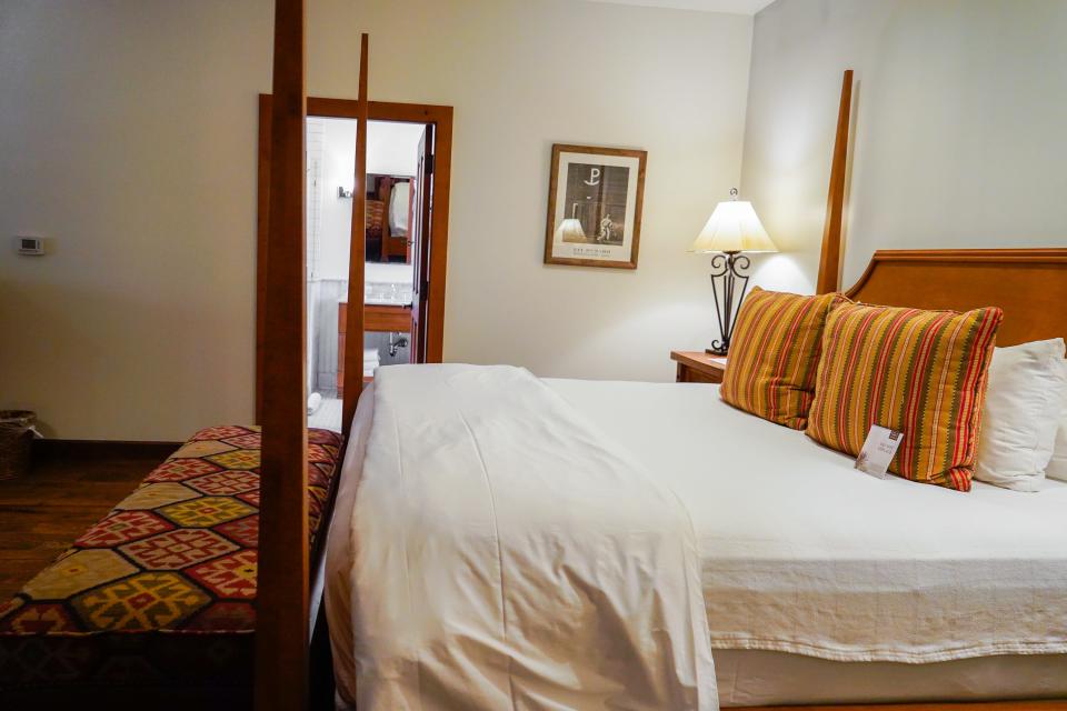 A king bed with white sheets and tall posts