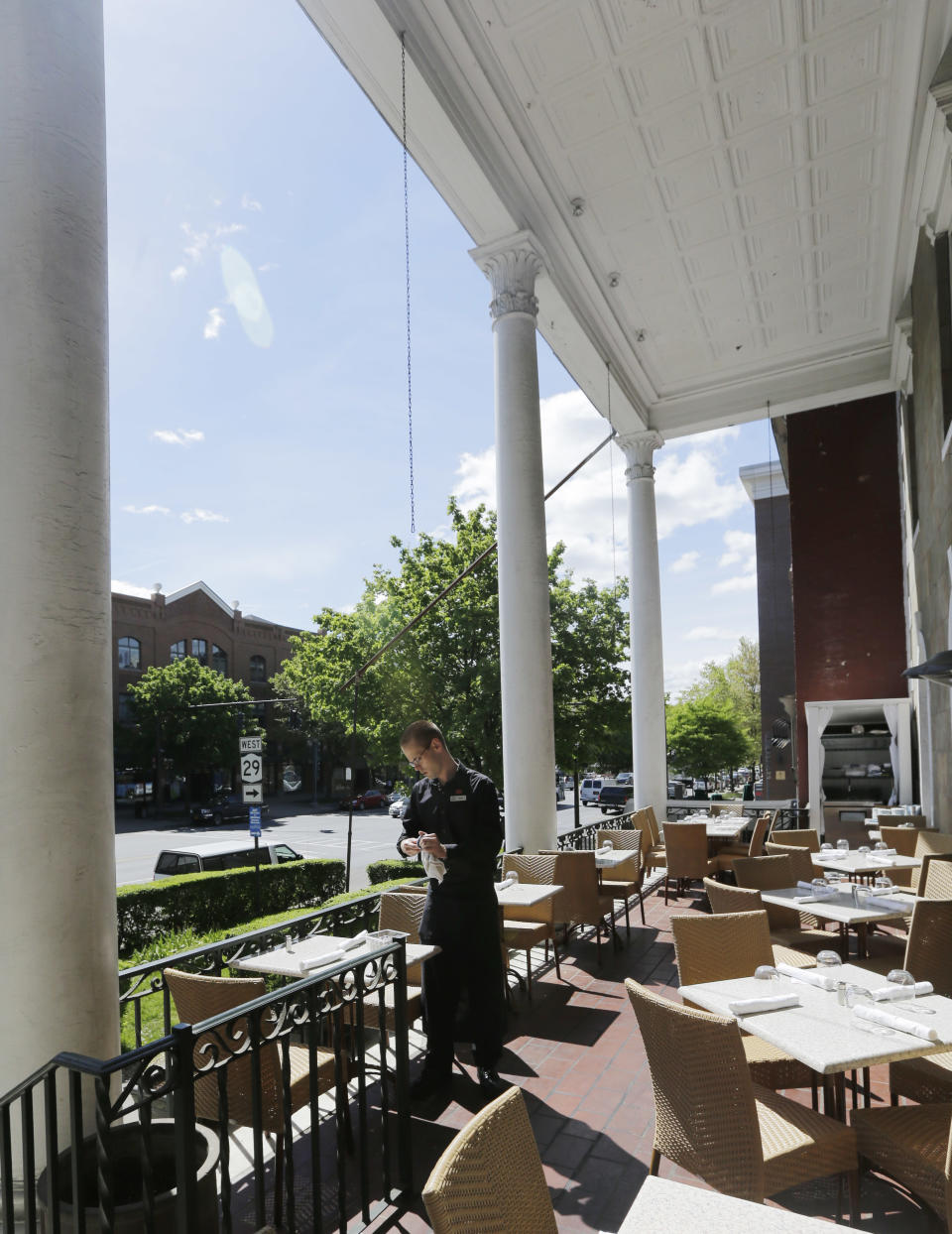 This May 17, 2013 photo shows waiter Ryan Benway setting tables before the lunch crowd arrives at Maestro's at the Van Dam American Bistro in Saratoga Springs, N.Y. Saratoga Springs' racetrack is still going strong as it marks its 150th anniversary this summer, the centerpiece attraction in a town that's also known for mineral springs, Victorian charm and upscale hotels, shops and restaurants. (AP Photo/Mike Groll)