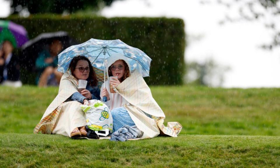 Two spectators shelter from the rain at Wimbledon