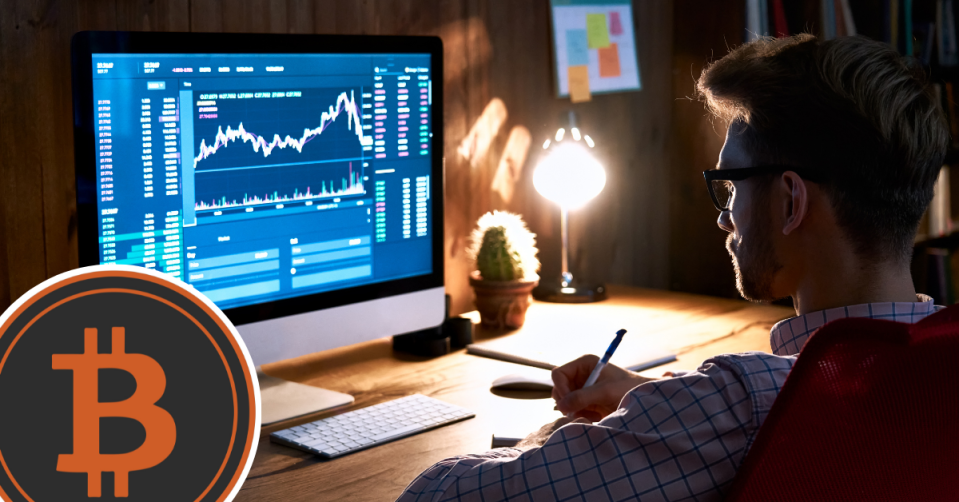 Man at computer watching trading position with Bitcoin symbol on the side.