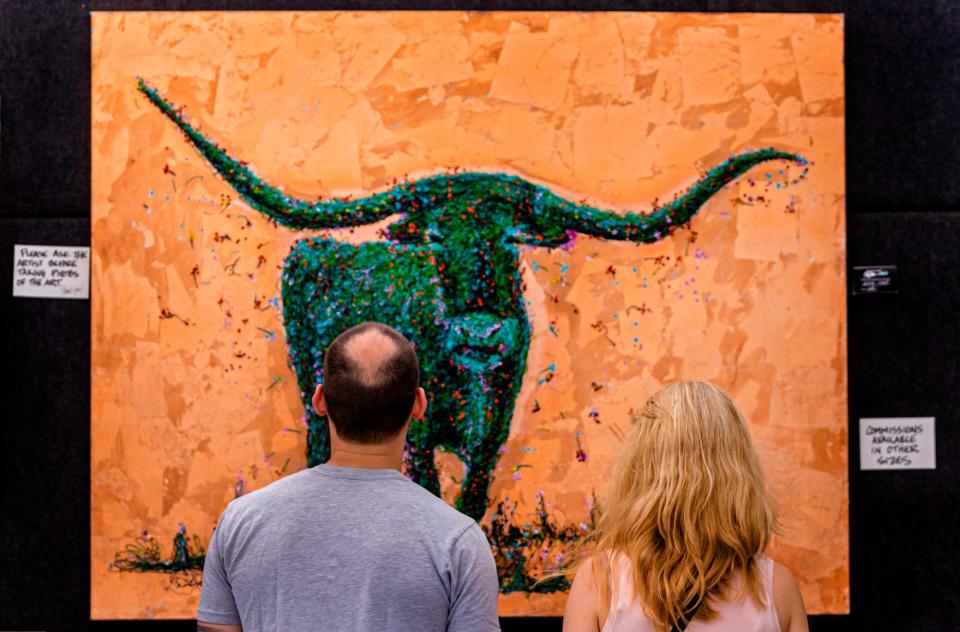 A couple take a closer look at artwork on display Sept. 6, 2021, during the Paseo Arts Festival in Oklahoma City.