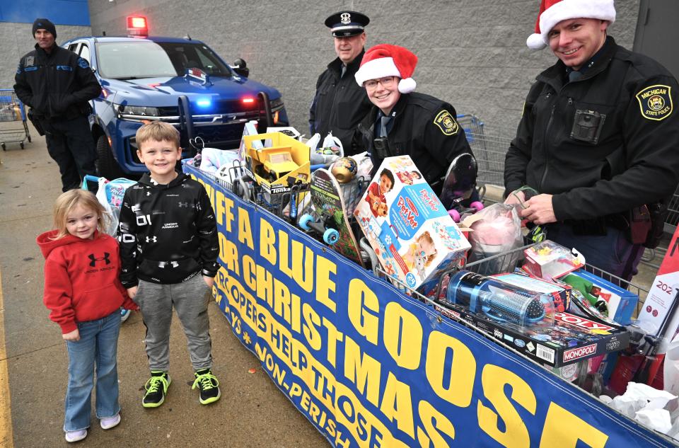 Daryl Trufant of Coldwater hands over his donation to trooper Zoey Feighner as Det. Sgt. Matt Berry and Cody Boatman look on at the Coldwater Walmart Saturday.