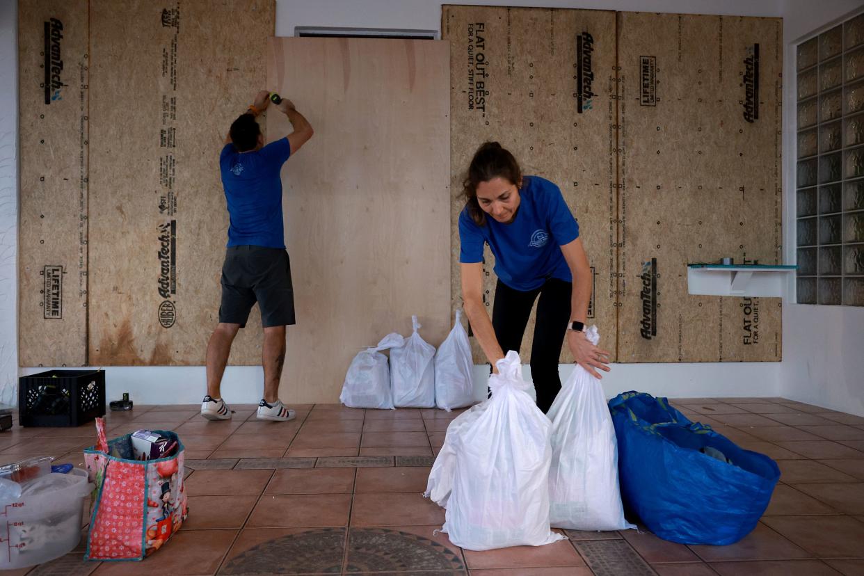 Luca Leguerchois (L) and Eglantine Leguerchois board up their Paradise Sweets store in preparation for Hurricane Ian on Sept. 26, 2022, in St. Petersburg, Fla.