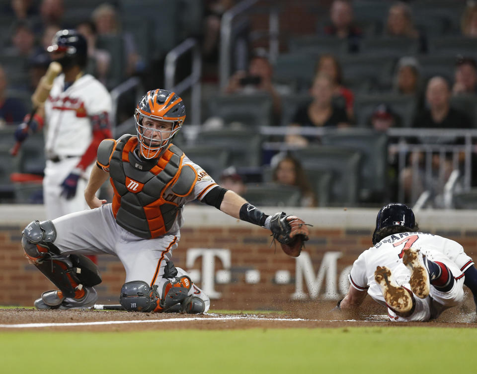 Shortstop Dansby Swanson #7 of the Atlanta Braves slides into home plate behind the tag of catcher Buster Posey #28 of the San Francisco Giants in the second inning during the game at SunTrust Park on September 21, 2019 in Atlanta, Georgia. / Credit: Getty Images