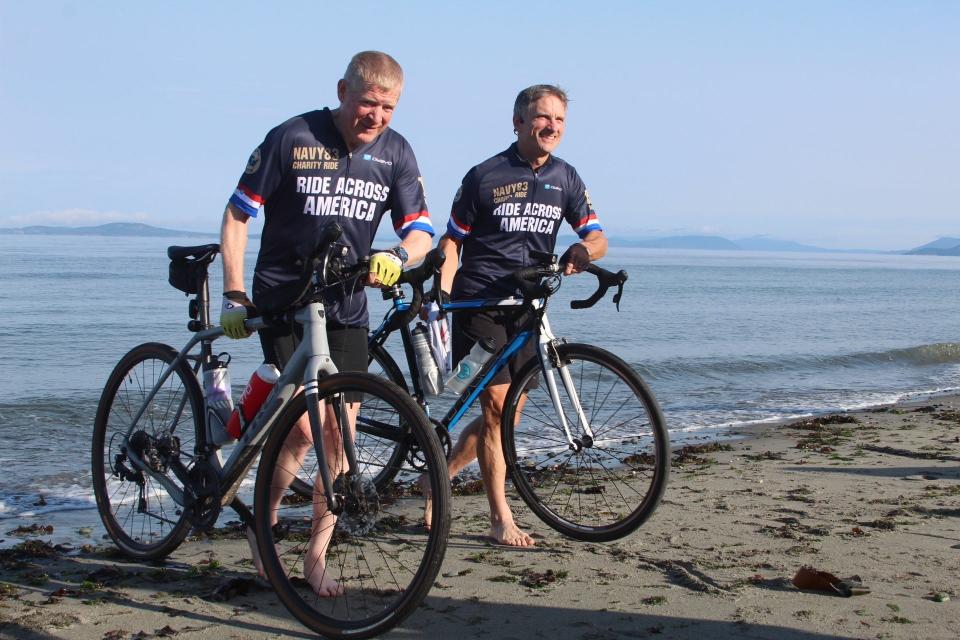 Mike Kohrs, left, and Bill Murray, two Wisconsinites on the ride across America, dip their tires in the Salish Sea at Naval Air Station Whidbey Island in Oak Harbor, Washington.