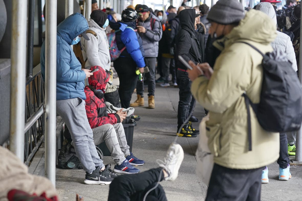 Recent immigrants to the United States sit with their belongings on the sidewalk in front of the Watson Hotel in New York, Monday, Jan. 30, 2023. (AP Photo/Seth Wenig, File )