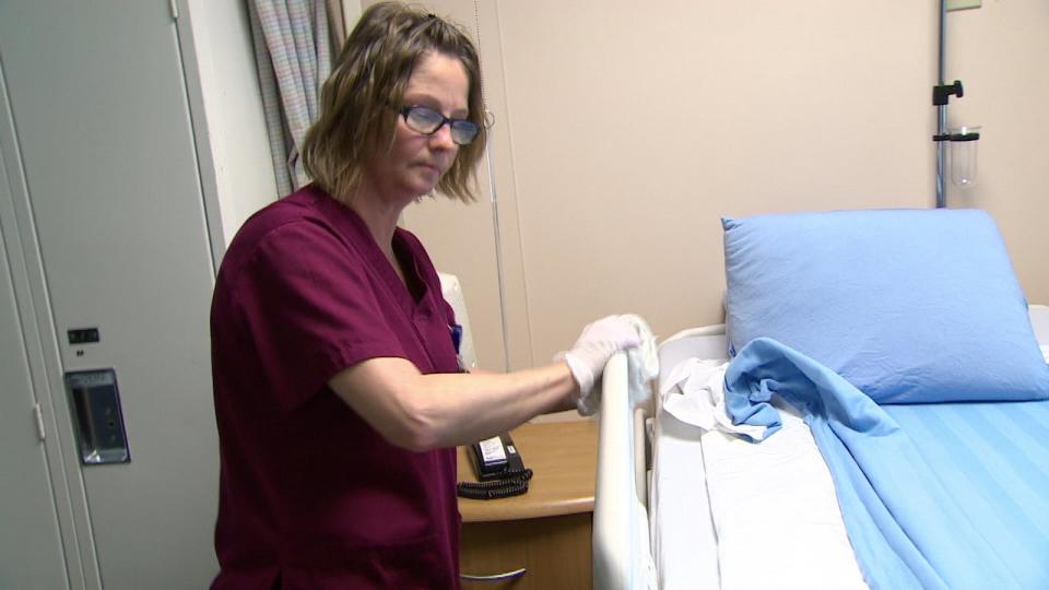 A New Brunswick hospital worker wipes down a hospital bed railing. 